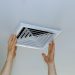 Close up man hand installing vent cover from ceiling Mounted Air Conditioner.